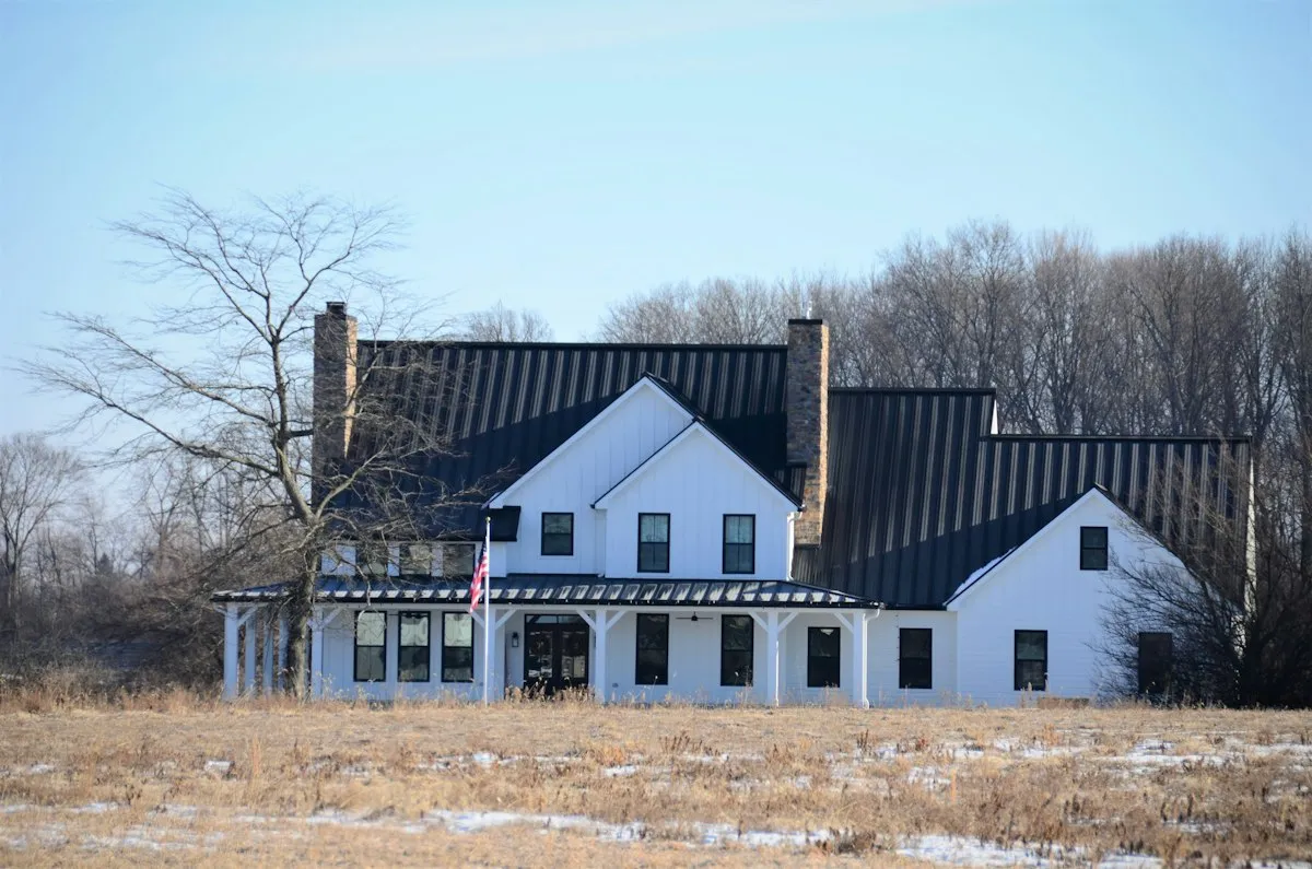 Black 6-inch K-style seamless gutters matching a black metal roof on a white farmhouse