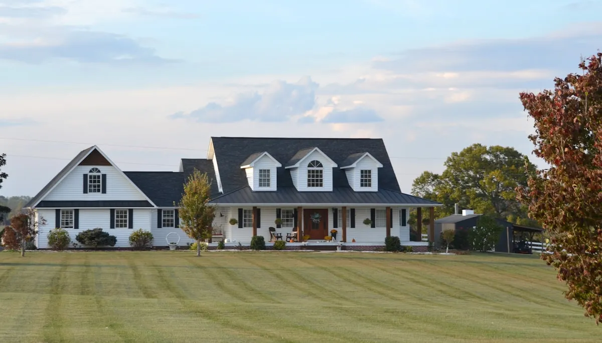 Dark charcoal-black 6-inch K-style seamless aluminum gutters on a white farmhouse with dormers